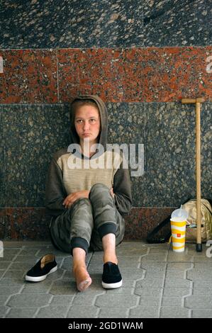 Homeless young disabled girl begging for money sitting on the pavement in the underground passage. August 7, 2021. Kyiv, Ukraine Stock Photo