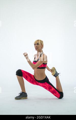Side view of lovely sporty young woman in red sport wear exercising. Isolated on white background. Caucasian, blond. High quality photo Stock Photo