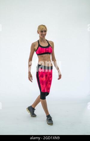 Fit young woman in red sportswear walking. Isolated on white background. Caucasian, blond. High quality photo Stock Photo