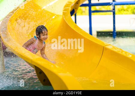 Closeup of a little girl sliding down on a yellow waterslide. Stock Photo