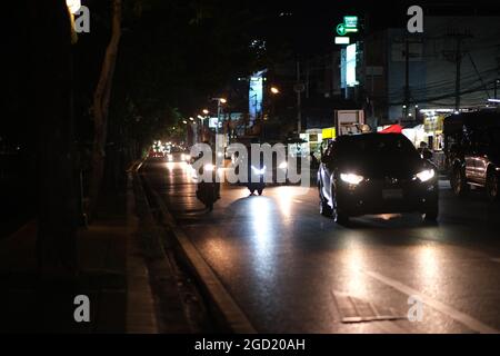 A road in big city at late evening: heavy traffic under a big trees in Chiang Mai, Thailand Stock Photo