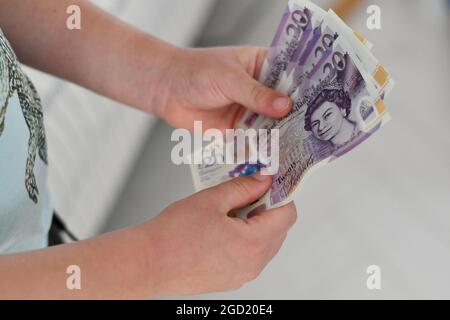 A little boy holding one hundred pounds is twenty pound notes, Sterling Stock Photo
