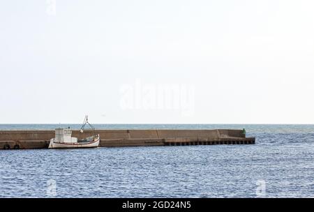 Fishing boat inside breakwater on Swedish east coast. Stock Photo