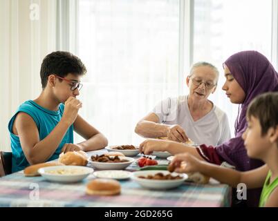 Happy family enjoying eating food in dining room Stock Photo