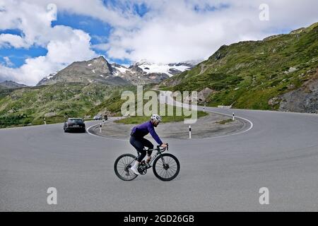 Road cyclist on the mountain pass Bernina, Passo del Bernina, in the Swiss Alps. The Bernina Pass connects the cantons of Graubünden and Engadin. Stock Photo