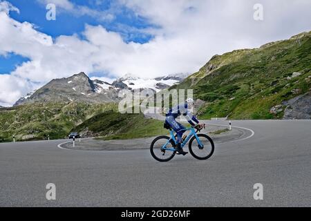 Road cyclist on the mountain pass Bernina, Passo del Bernina, in the Swiss Alps. The Bernina Pass connects the cantons of Graubünden and Engadin. Stock Photo