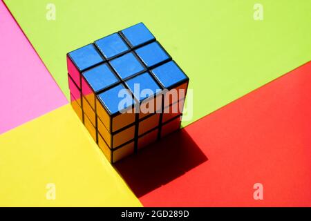 Rubik's cube by blue side on a sunny colorful table. Stock Photo