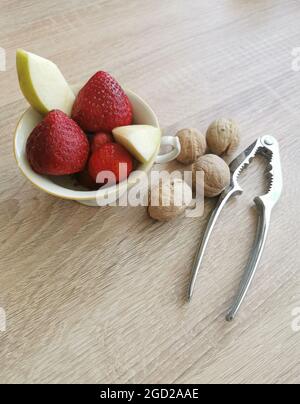 Fresh strawberries, apple pieces, walnuts and a nutcracker Stock Photo