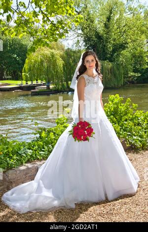 Bride in traditional white bridal dress with red rose bouquet just married, posing in riverside church grounds with bunch of red roses Stock Photo - Alamy Bride in traditional white bridal dress with red rose bouquet just married, posing in riverside church grounds with bunch of red roses Stock Photo - Alamy