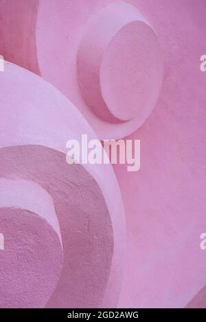 Detail of volume stone sculpture with twirl shapes. Pink concrete convex background Stock Photo