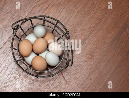 10 eggs in a iron egg basket shot from overhead.  Eggs are from free range hens and are 3 different colors. Stock Photo
