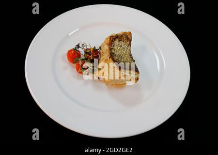 grilled atlantic cod fish fillet on a white plate with cherry tomato Stock Photo