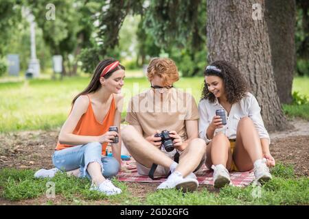 Three young friends with drink looking photo on camera Stock Photo