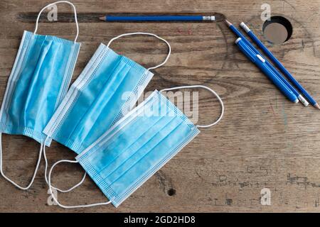 face mask and blue pencil on vintage wood desk shot from above with copy space Stock Photo