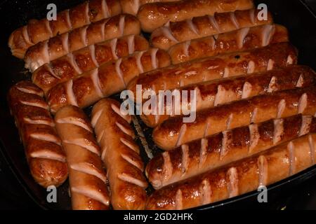Closeup of smoked sausages being fried in a pan for breakfast Stock Photo