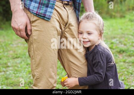 Portrait of a happy little girl 2-3 years old holding on to her dad's leg Stock Photo