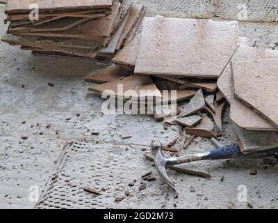 Hammer with broken ceramic floor tile on concrete Stock Photo
