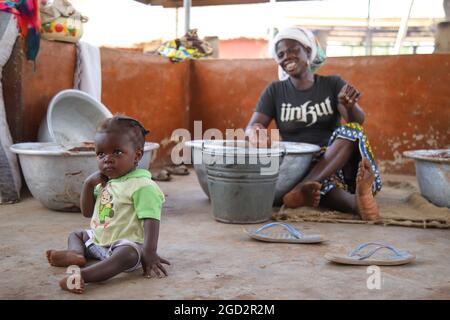 A West African village woman works with her child ca. 20 February 2018 Stock Photo