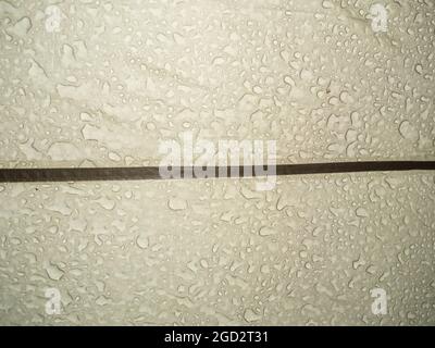 Big rain drops on the surface of a tourist tent taken close-up from inside, drops contours Stock Photo