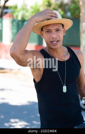 Handsome latino man holding his hat in place: Selective focus. Diversity and lifestyle concept. Stock Photo