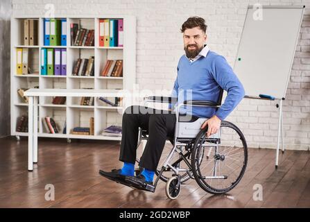 Smiling disabled businessman sitting in a wheelchair at his office Stock Photo