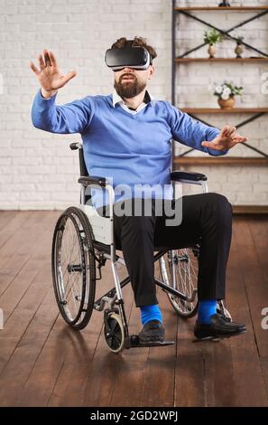 Adult man sitting in a wheelchair and using a VR headset Stock Photo