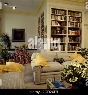 Floor to ceiling shelving unit on l-shaped designer livingroom in NYC eighties Stock Photo