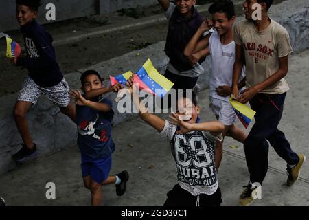 Caracas, Venezuela. 10th Aug, 2021. Children wave flags of Venezuela and run alongside the bus in which the Venezuelan team travels through the city after its participation in the Tokyo Olympics. Credit: Jesus Vargas/dpa/Alamy Live News Stock Photo