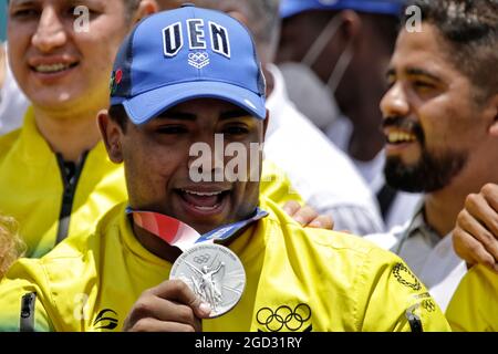 Caracas, Venezuela. 10th Aug, 2021. Keydomar Vallenilla (m.) shows his Olympic medal while being cheered by fans after his arrival after the Tokyo Olympics. Vallenilla won silver in Tokyo in the 96kg total. Credit: Jesus Vargas/dpa/Alamy Live News Stock Photo