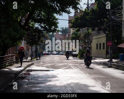 Medellin, Colombia - July 30 2021: Street with Little Traffic, with Trees on the Edges and People Walking on the Sidewalks in a Sunny Day Stock Photo