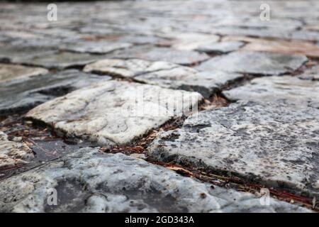 Ancient cobblestone pavement. Paving stone road close-up after rain. Summer travel Mediterranean historical landmarks Stock Photo