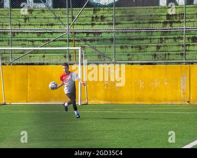 Medellin, Colombia - July 30 2021: A Young Latin Teenager in Sportswear is Practicing Kicking a Ball on a Synthetic Grass Field Stock Photo