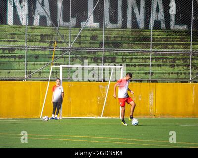 Medellin, Colombia - July 30 2021: Two Young Latin Teenagers in Sportswear Training Soccer with Several Balls on a Sunny Day Stock Photo