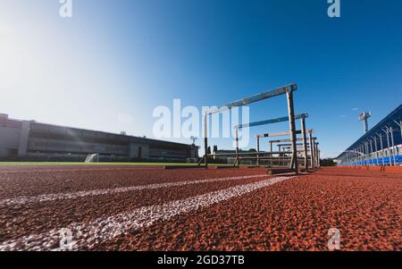Hurdle race barrier on stadium track at sunny day. Blue sky. Stock Photo