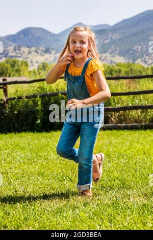Young girl playing & running in grassy yard Stock Photo