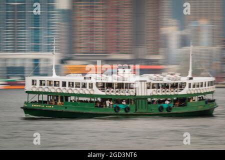 Motion blur treatment of the 'Meridian Star', one of the Star Ferry fleet, passing the highrise apartment blocks of Union Square in West Kowloon Stock Photo