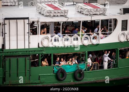 Tourists take photographs aboard the 'Solar Star', one of the Star Ferry fleet, as it approaches Central Ferry Pier 7 on Hong Kong Island Stock Photo