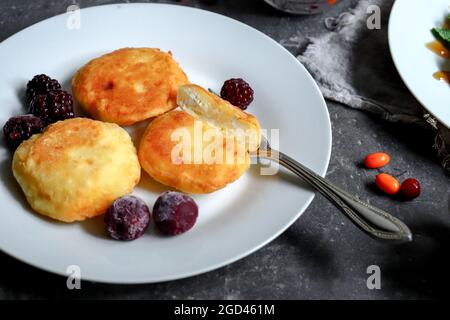 Sweet curd pancakes with berries for breakfast. Cottage cheese pancakes. Close up. Dark background. Copyspace. Summer dessert. Stock Photo