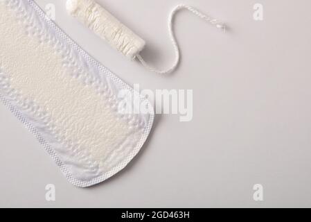Background with female protectors for the menstrual cycle. Pantiliner and tampon on white background. Top view. Horizontal composition. Stock Photo