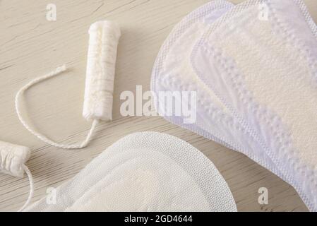 Background with female absorbent protectors for the menstrual cycle. Pantiliner,napkin and tampon on white wooden table. Top view. Horizontal composit Stock Photo