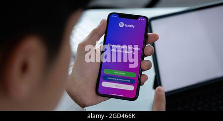 CHIANG MAI, THAILAND - APR 06, 2021: Person holding a brand new Apple iPhone XS with Spotify logo on the screen. Spotify is a popular commercial music Stock Photo