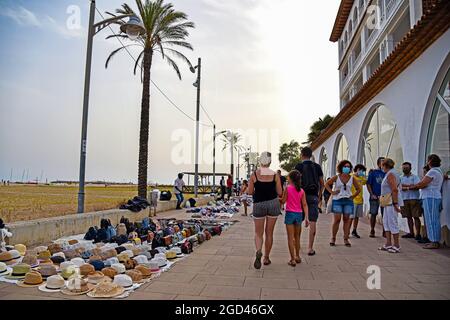 Vendrell, Spain. 05th Aug, 2021. People walk in front of the illegal  products sold by street vendors in Vendrell. Illegal street vendors known  as 