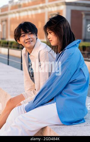 Cool young asian couple sitting in the city and having fun. Stock Photo