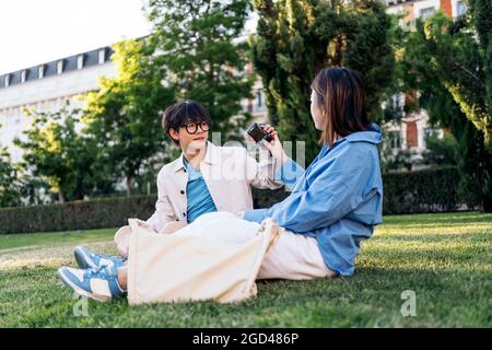 Unrecognized woman taking photos to her asian boyfriend in the park. Stock Photo