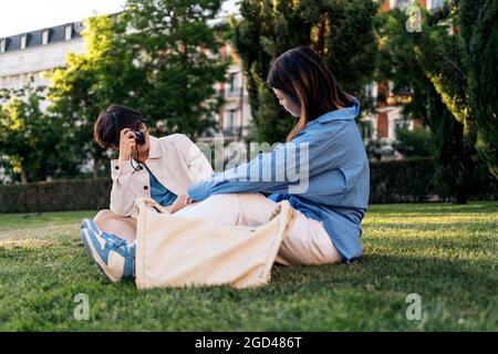 Unrecognized man taking photos to his asian girlfriend in the park. Stock Photo