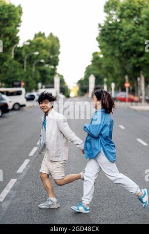 Young asian couple holding hands having fun in the city and looking at camera. Stock Photo