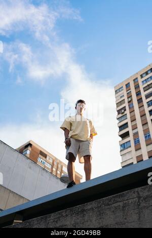 Confident young man wearing casual clothes posing and looking at camera in the city. Stock Photo
