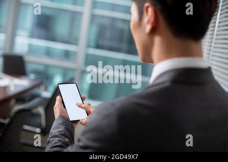 Confident businessman using smartphone in office Stock Photo
