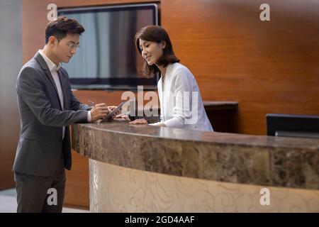 Businessman checking in at front desk Stock Photo