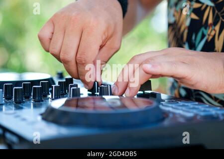 DJ Hands creating and regulating music on dj console mixer in beach club stage.  Stock Photo
